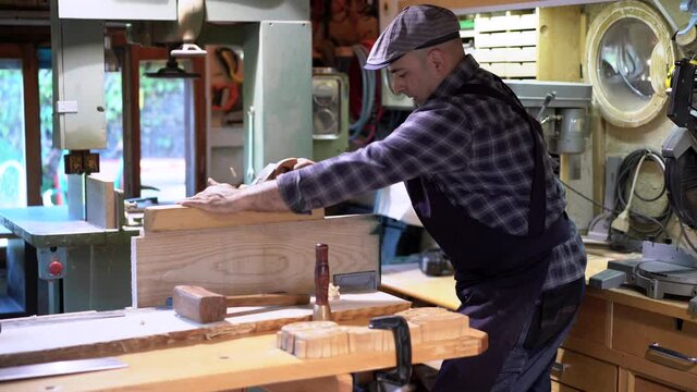 Carpenter planing wooden board with jointer