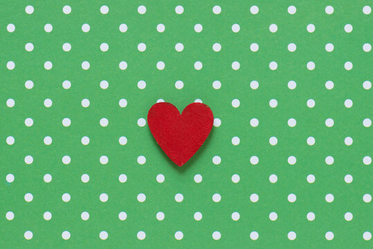 single hand painted red heart on a halftone printed green and white dot background