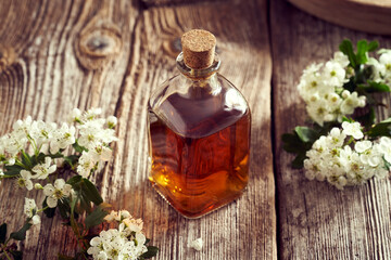 A bottle of hawthorn tincture with blooming hawthorn twigs