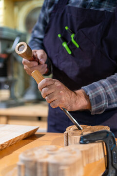 Craftsman carving wooden detail in workshop