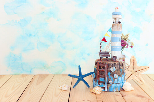 Nautical concept with sea life style objects as driftwood beach house, seashells and starfish over wooden table