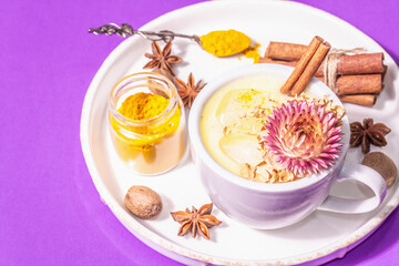 Golden turmeric milk with ice on bright yellow background