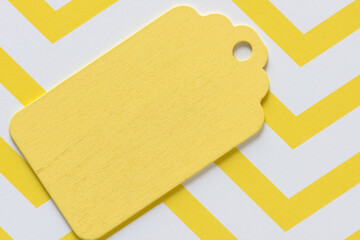 retro wooden pastel yellow gift or merchandise tag or label isolated on yellow and white zig zag...
