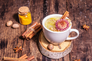 Golden turmeric milk with ice on bright yellow background