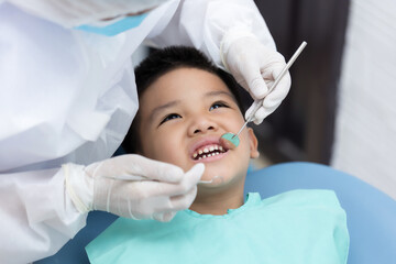 Dentist examining Asian little boy teeth in clinic.