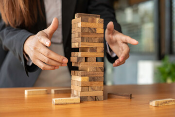 businesswoman holds her hand on a wooden block with a weak base. It is like a business risk...