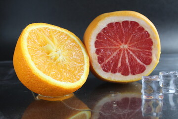 orange and grapefruit in the cut lie next to ice cubes on a black background. Fruit for lemonade. citrus