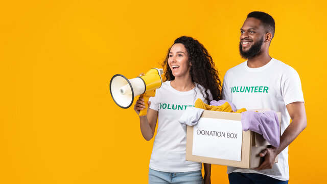 Multiethnic Volunteers Holding Donation Box Talking In Megaphone, Yellow Background