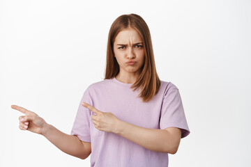 She dislikes it. Pouting girl pointing left at smth unfair, furrow eyebrows and complain, whining...