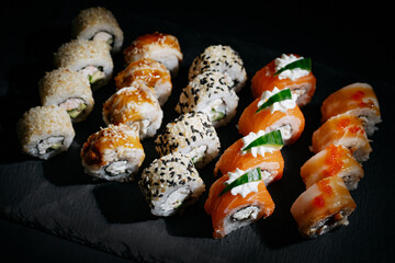 Assorted bright rolls with fish, cheese, eel, perch, caviar and soy unagi sauce on a stone board