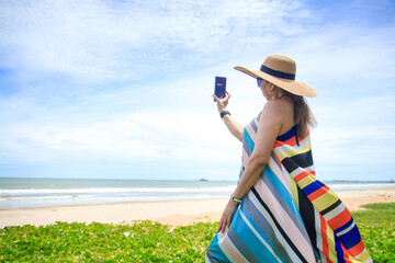 stylish woman wearing a colorful long dress Stand in the sunshine at the seaside looking at the beautiful natural scenery. Tourist sea beach Thailand, Asia, Summer holiday vacation travel trip.