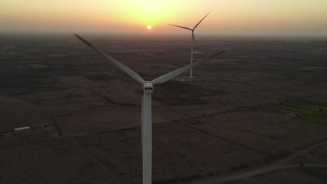 Large wind turbines with blades in field aerial view bright orange sunset