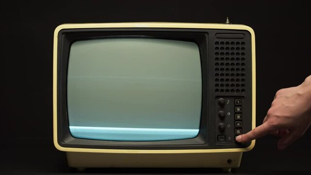 Close-up of switching channels on old retro television on black background, tv setting. Broken old-fashioned TV with noise screen, bad signal reception, cinematography concept.