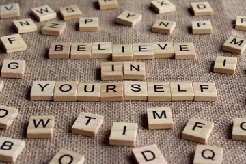 Selective focus image of wooden cube with text BELIEVE IN YOURSELF