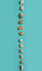 Small stones similar to pebbles lying on a turquoise background vertically.