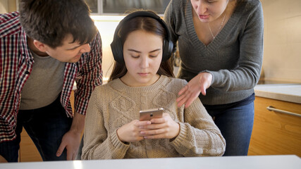 Teenage girl listening music and using smartphone while parent shout and argue with her. Family violence, conflicts and relationship problems