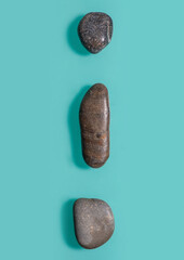 3 small stones, similar to pebbles, vertically lie on a turquoise background.