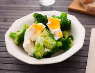 boiled broccoli inflorescences with boiled egg in plate