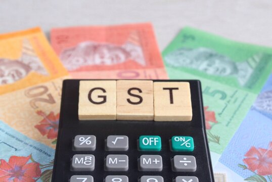 Selective focus image of calculator and Malaysia ringgit banknotes with text GST