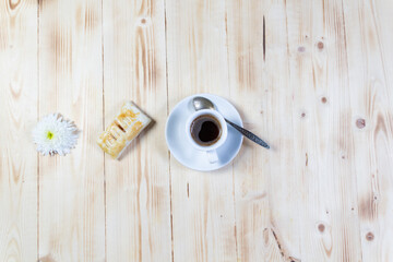 Small cup of black coffee, cookies on white plate,  daisy chrysanthemum flower on wooden table