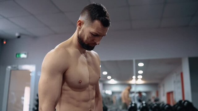 The profile frame of the bodybuilder who looks seriously ahead, has a bare chest, in the gym. Intense masculine energy. Healthy lifestyle. Sport concept