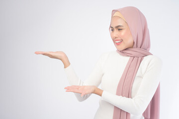 Portrait of young smiling muslim woman wearing a pink hijab over white background studio.