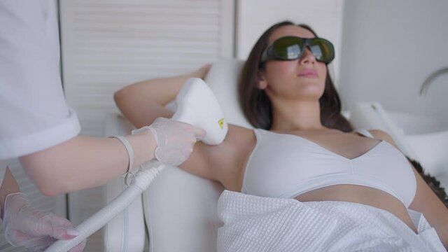A female cosmetologist does laser hair removal of the armpits in a beauty salon. Removal of hair from the armpits. Beauty and clean skin