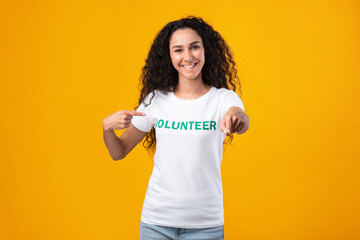 Joyful female volunteer activist pointing at camera posing in studio