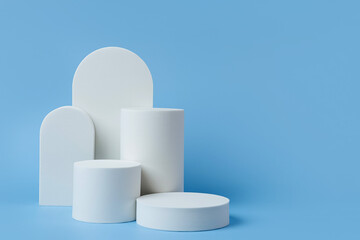 White podium to show cosmetic products with geometric forms on blue background. Background for branding and packaging presentation. Natural skincare beauty product concept.