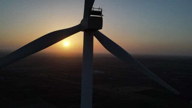 Large wind turbines with blades in field aerial view bright orange sunset