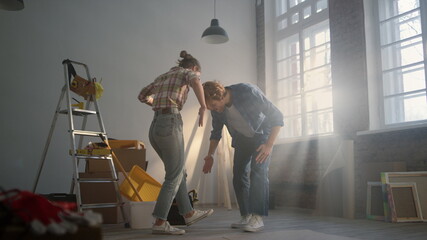 Cheerful couple having fun indoors. Joyful family dancing in new apartment..