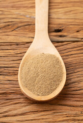 Closeup of ground cumin on a spoon over wooden table
