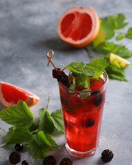 Soft drinks. Berry mojito with grapefruit, blackberries and currants with ice and fresh mint in a transparent glass on a light background. Summer. Background image, copy space