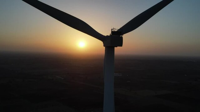Large wind turbines with blades in field aerial view bright orange sunset