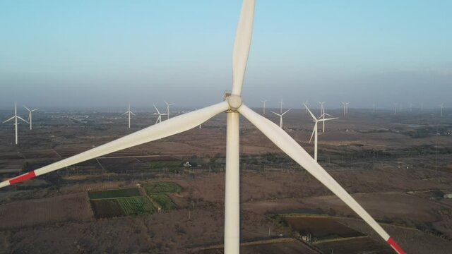 Aerial view over the farm landscape and wind turbines generating clean renewable energy. Renewable energy production for the green ecological world.