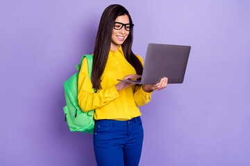 Full size photo of cheerful young nice woman look hold computer wear glasses isolated on violet color background