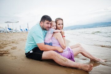Summer vacations. Parents and people outdoor activity with children. Happy family holidays. Father, pregnant mother, baby daughter on sea sand beach.