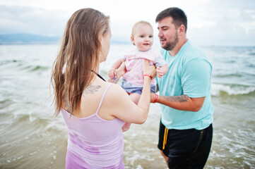 Summer vacations. Parents and people outdoor activity with children. Happy family holidays. Father, pregnant mother, baby daughter on sea sand beach.