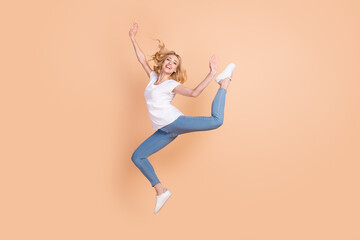 Full length body size photo blonde woman cheerful jumping like ballerina isolated pastel beige color background