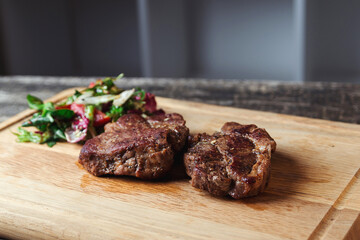 Tasty juicy grilled steak and salad with tomatoes on cutting board. Main course beef dinner.