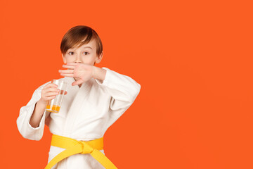 Boy in white kimono drinks water. Healthy sporty childhood and lifestyle. Martial arts, school and training.