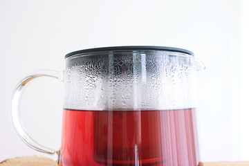 Forest berry tea inside glass tea pot with dew on outside close up isolated front view