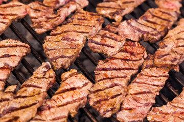 Beef meat is grilled, close-up. Beef steaks on a grill grid.