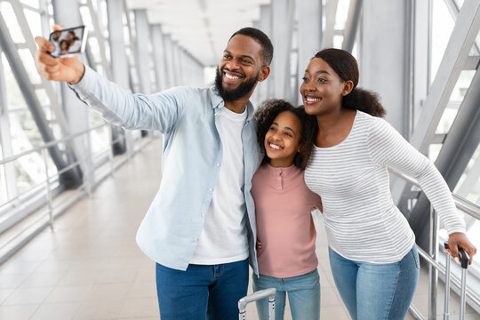 Black family traveling, taking selfie on cellphone in airport