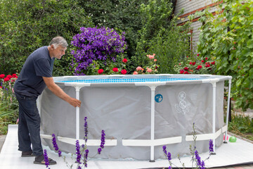Installing the pool on a warm summer day. A man and a boy are assembling a frame pool.