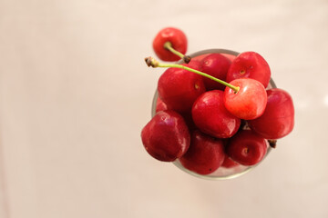 Bunch of sweet cherries in a glass on a beige background. Copy space. Top view.