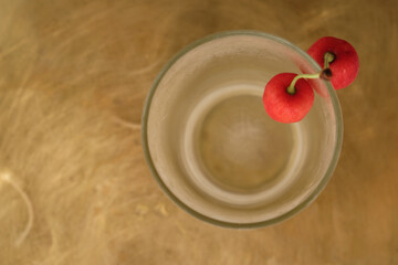 Earring of ripe sweet cherries on a chilled glass. Golden metal background. Copy space. Top view. 