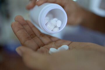 Close up Man hand pouring pills out of a bottle