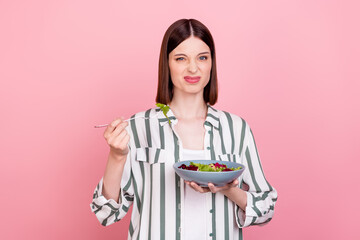 Photo of dislike brunette young lady eat salad wear white shirt top isolated on pink color...