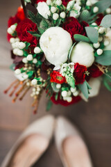 Pair of elegant and stylish bridal shoes and a bouquet of roses and other flowers